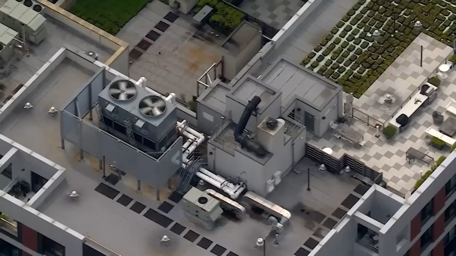 Two large metal cooling towers on a New York City building rooftop under overcast daylight