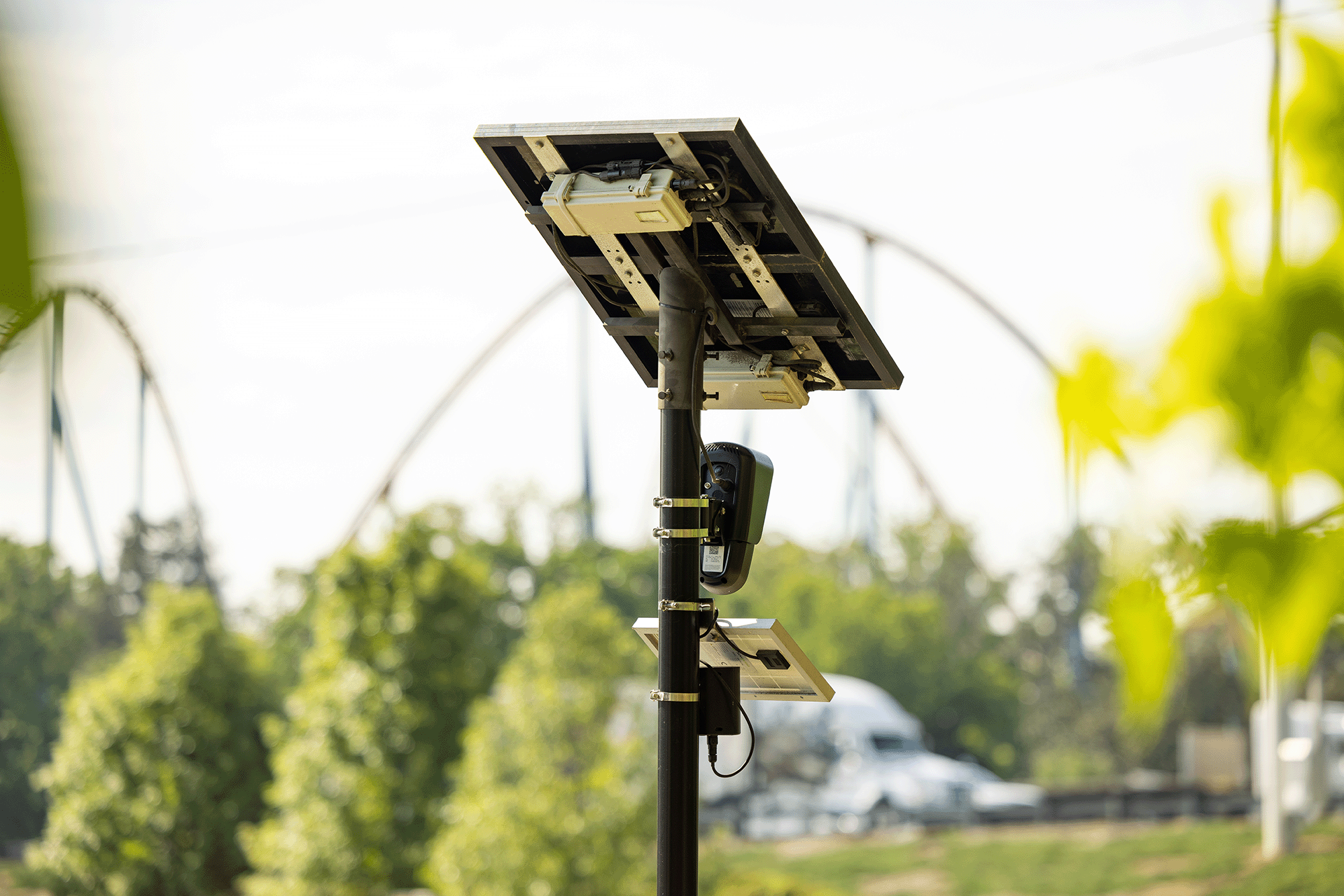 A Flock Safety Falcon camera and Raven audio sensor mounted together on a tall metal pole against a blue sky