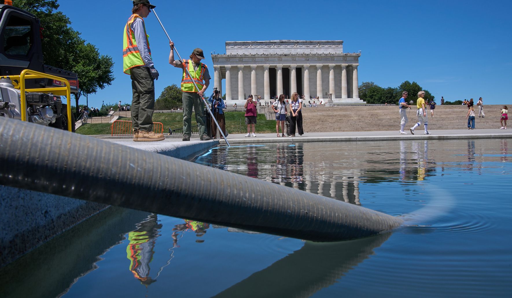 Large sections of blue coating peeling from the Lincoln Memorial Reflecting Pool floor with the Lincoln Memorial in the background