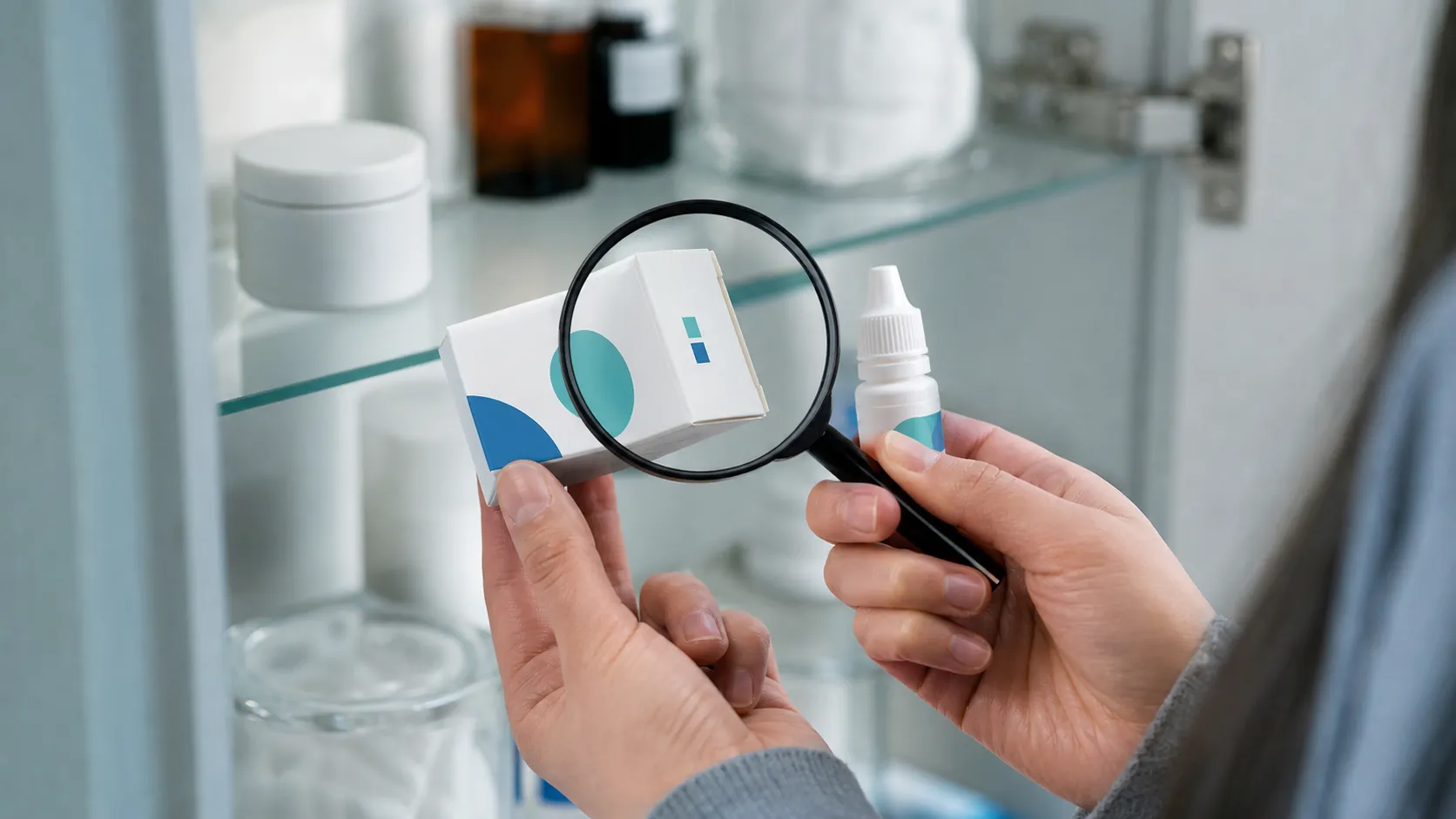 Hands holding a generic eye-drop carton and bottle while a magnifying glass hovers over the small printed code area