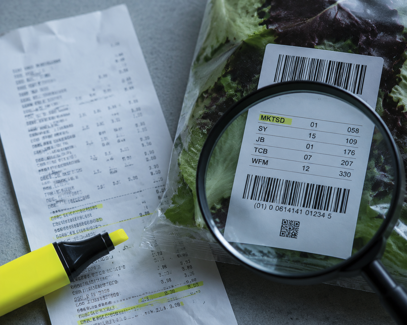 Magnifying glass over cryptic internal codes on a grocery receipt and bagged salad label