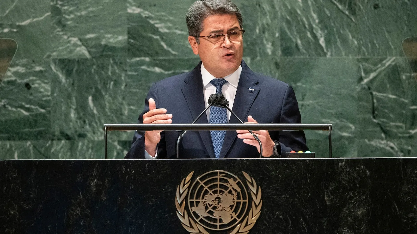 Former Honduran President Juan Orlando Hernández outside in a dark suit after release following Trump’s pardon